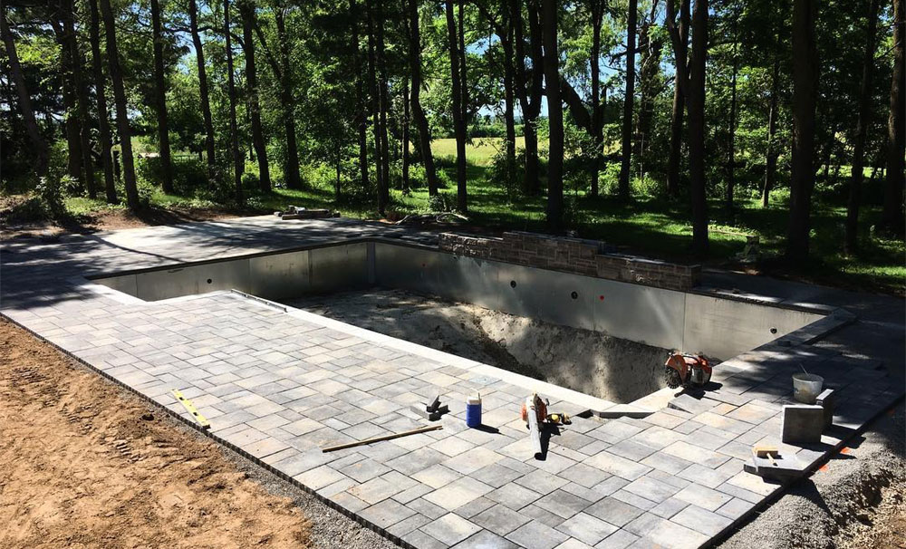 Patio being constructed around an in-ground pool